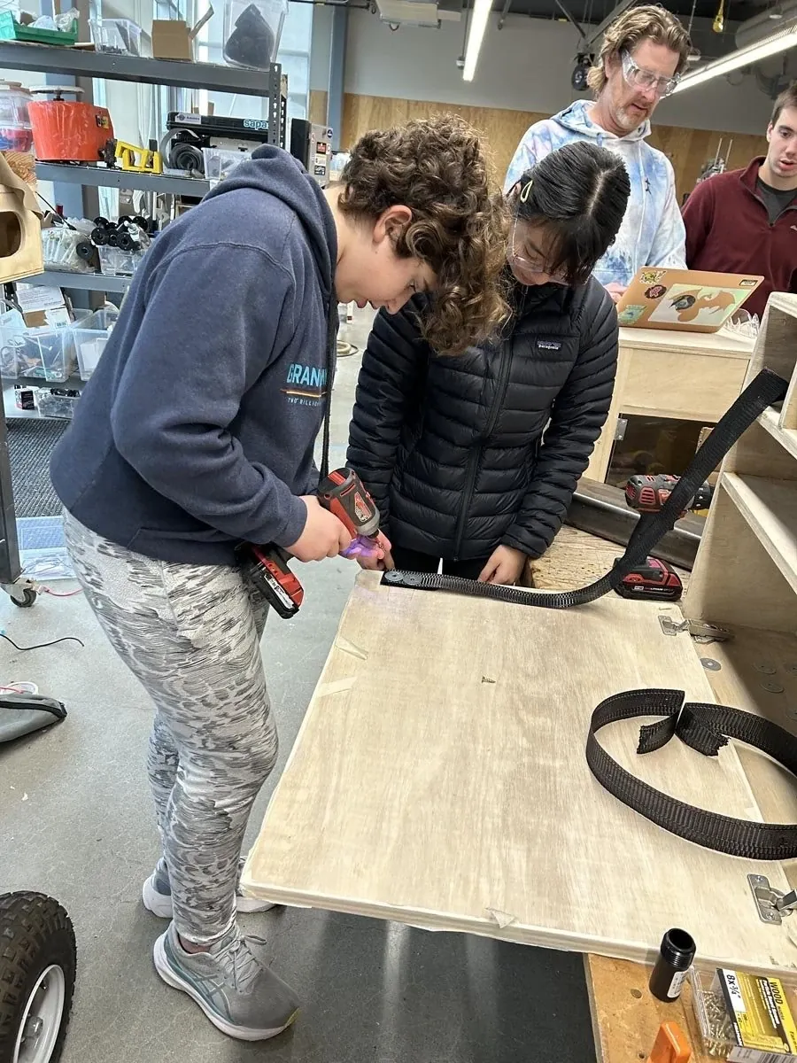 Students using clamps on a wooden project in the makerspace