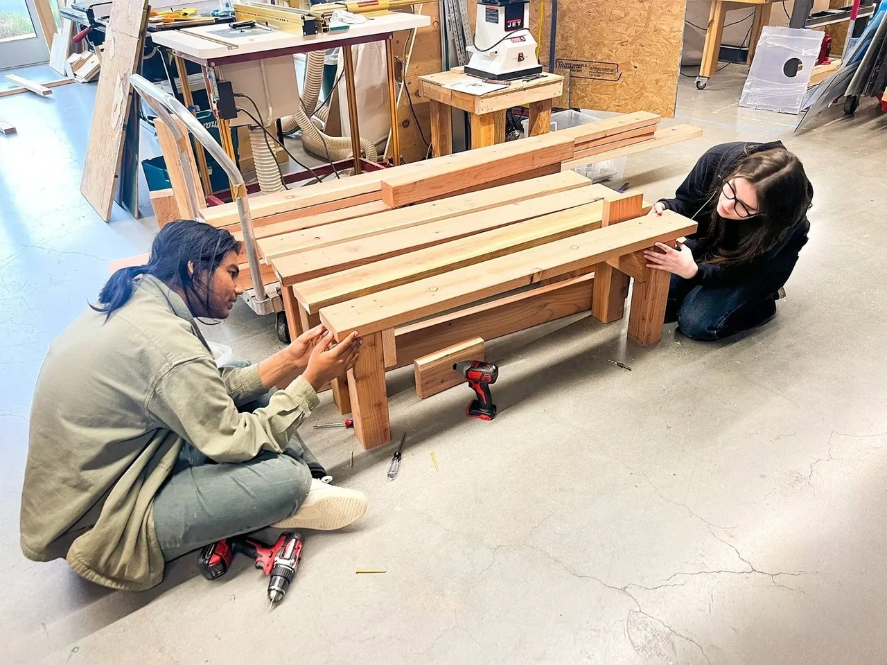 Students building a large wooden structure together in the makerspace
