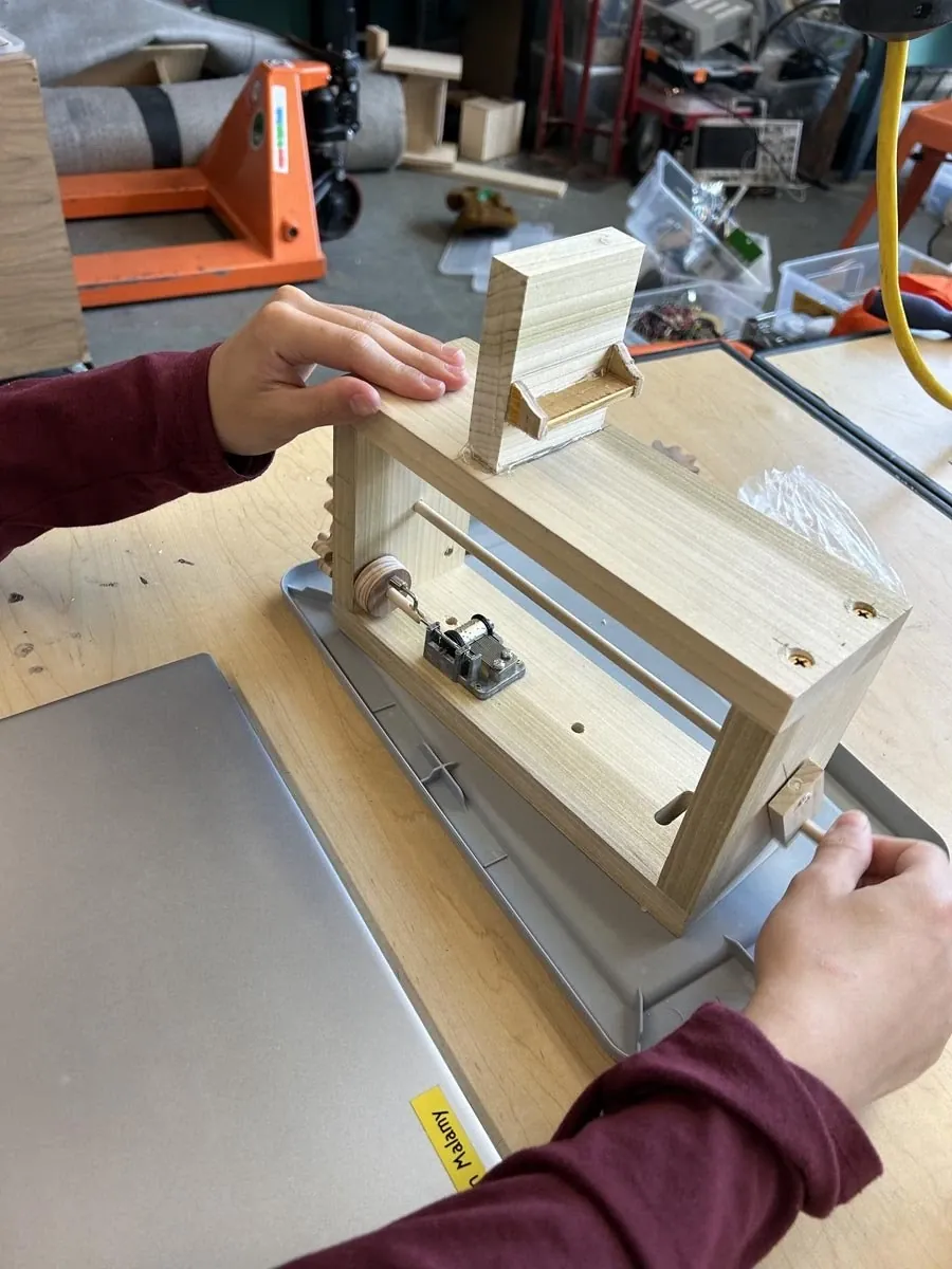 Hands demonstrating a handmade wooden prototype