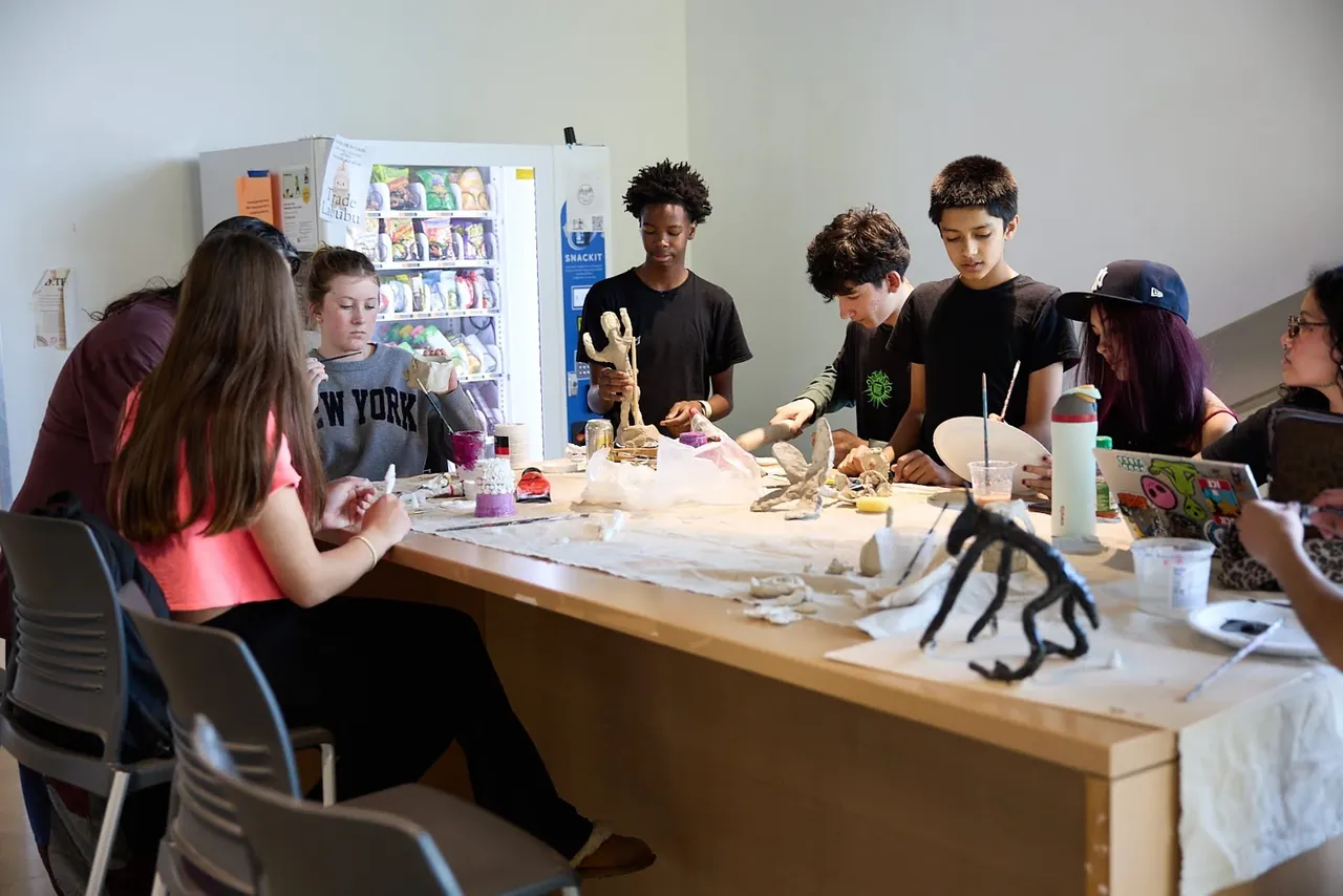 Students gathered around a workbench to discuss their projects