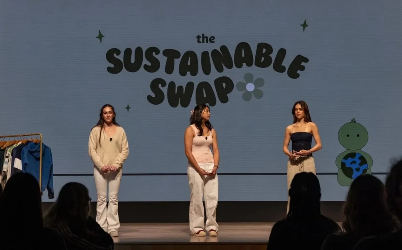 Three student presenters share their Sustainable Swap project at an event.